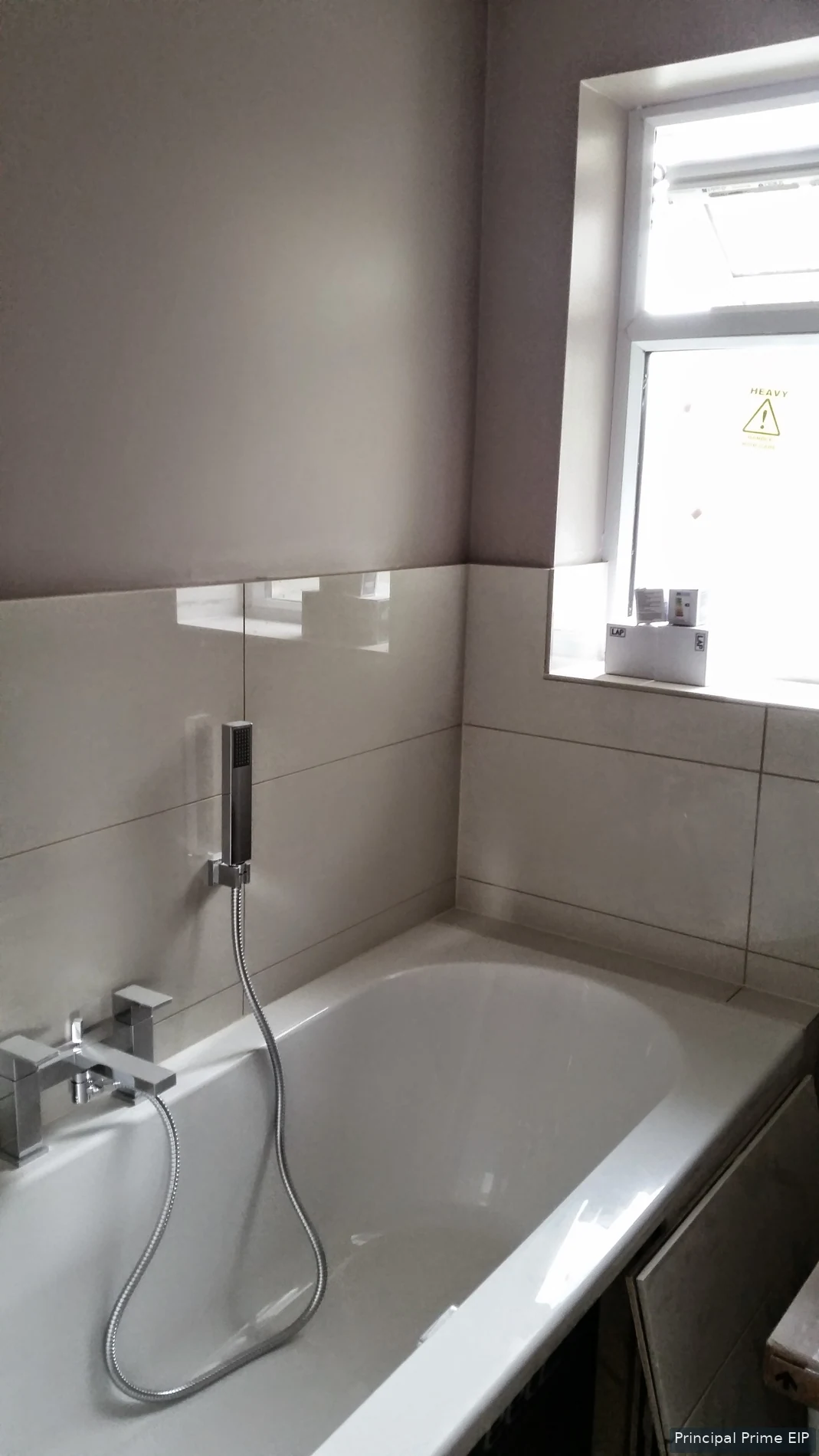 White bath with wall-mounted mixer and tiled surround White bath with wall-mounted mixer and tiled surround.